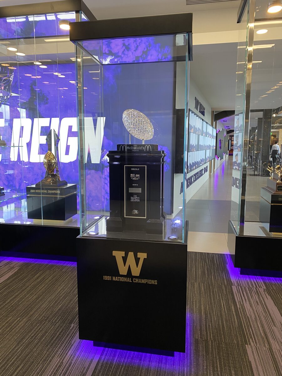 A crystal football trophy on a black pedestal inside a glass display case, with a gold W and the words 1991 National Champions on the base.