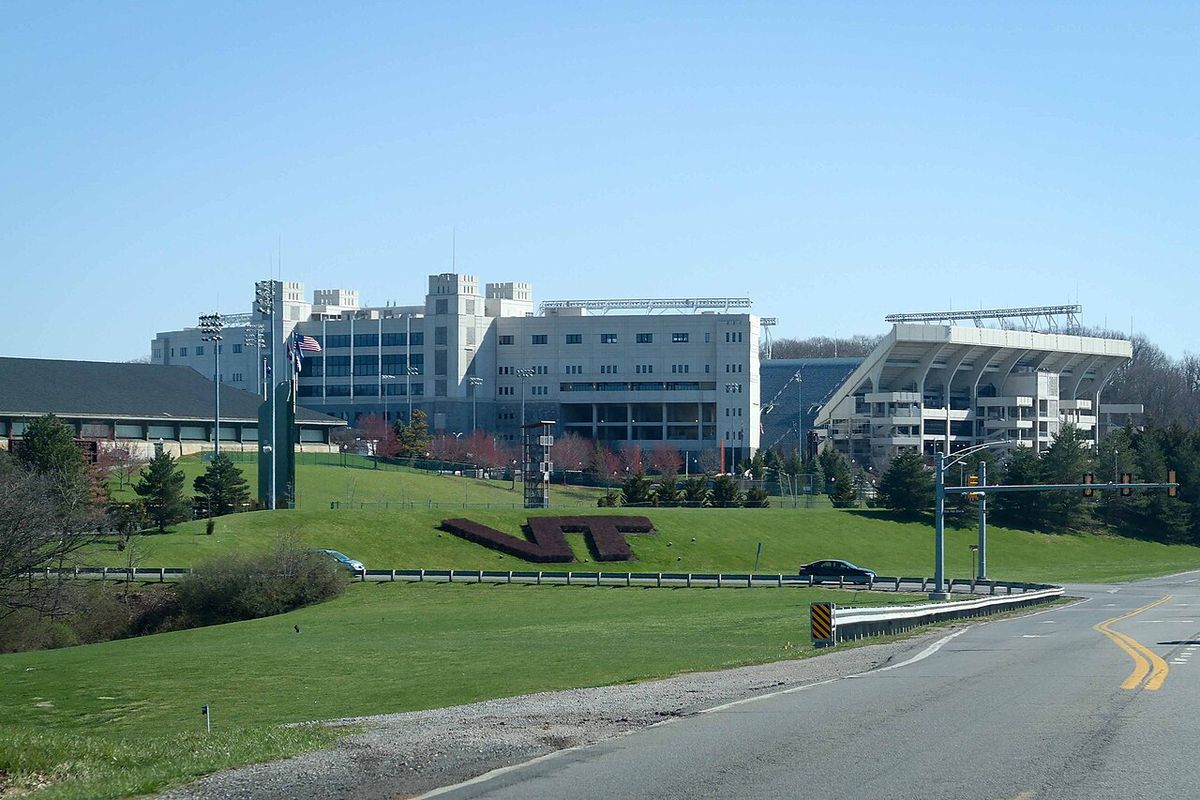 The outside of Lane Stadium at Virginia Tech on a sunny day, with a big VT logo on the grass.