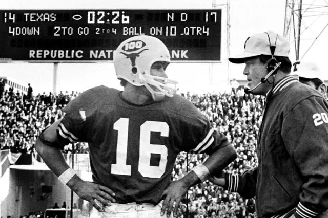 Black-and-white photo of Texas quarterback number 16 standing with hands on hips next to his coach, who wears a headset, with a scoreboard behind them showing Texas 14, Notre Dame 17, fourth down.