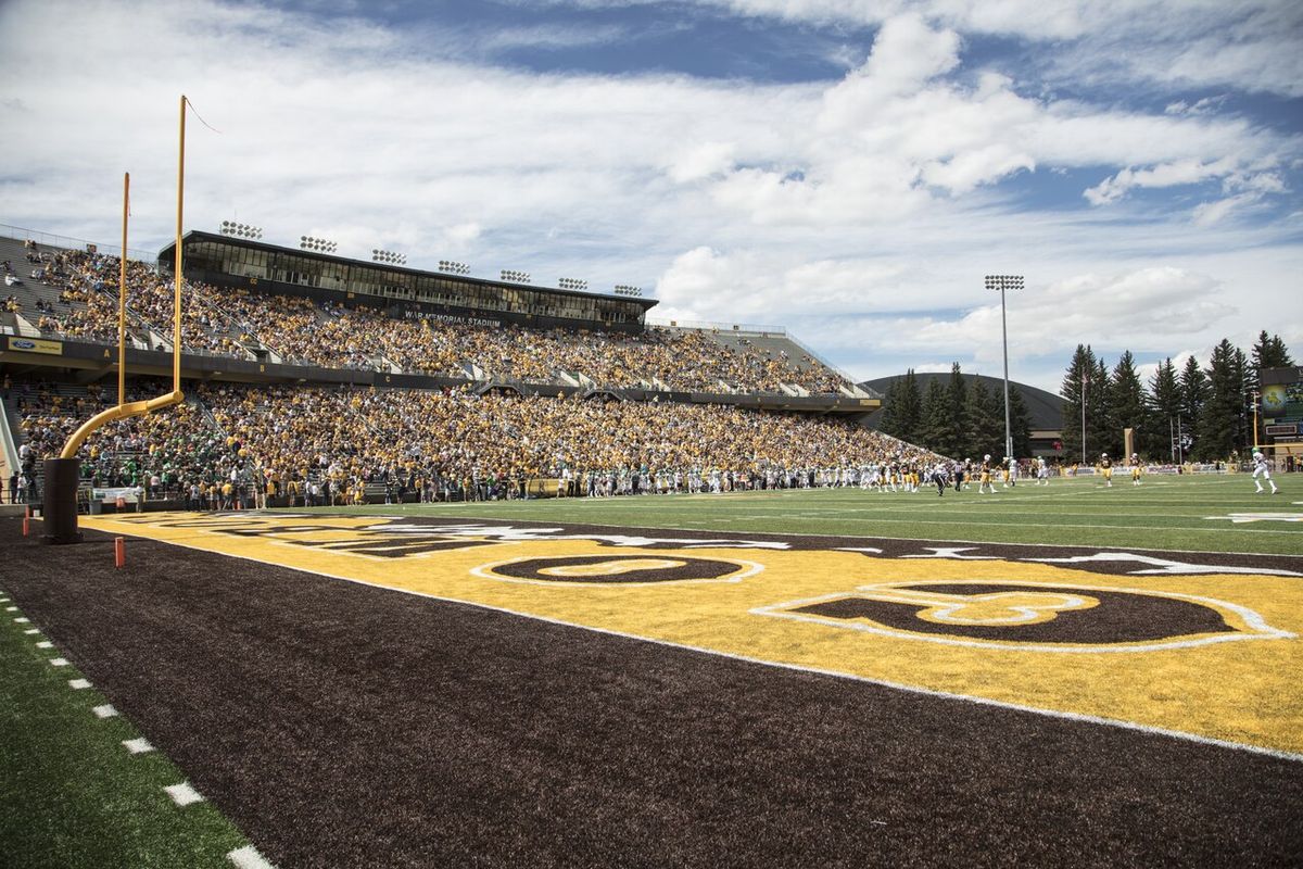The end zone and stands at Wyoming's War Memorial Stadium under a big sky with puffy clouds.